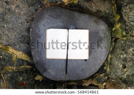 opened empty notebook with black bookmark on rounded gray stone, close up