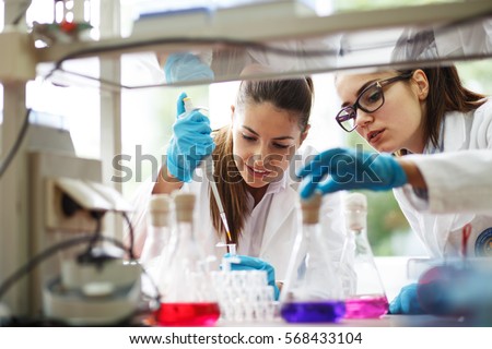 Two young female scientist doing experiments in lab. Royalty-Free Stock Photo #568433104