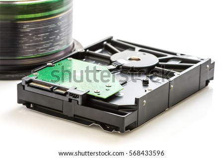 Hard disk drive (HDD) with circuit board and compact discs on white background