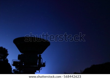 A millimeter wave telescope under the night sky is illuminated with city lights Royalty-Free Stock Photo #568442623
