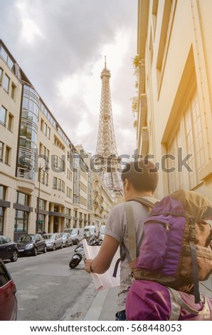 Travel concept . Asian Tourists backpack opening the map in Paris with Eiffel Tower France During a trip to through Europe.