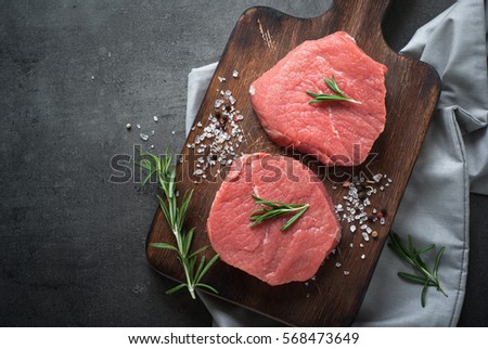 Raw meat. Raw beef steak on a cutting board with herbs and spices. Top view with copy space.