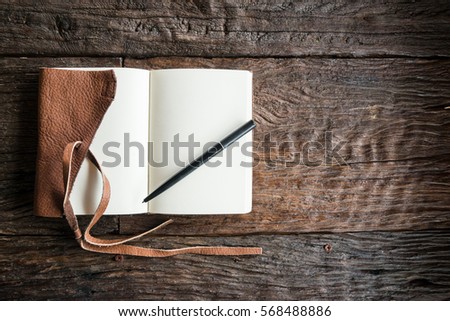 An opened diary leather book with blank space on the wood table. The education and learning concept.