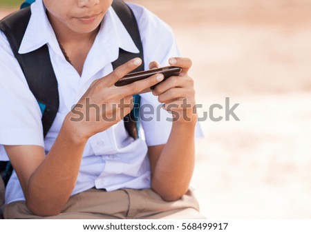 asian boy playing game with his smart phone