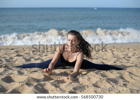 Active young beautiful woman doing stretching exercises on beach sandy outdoors background
