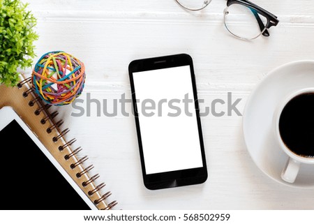 office desk table with blank phone on notebook and coffee cup / Top view with copy space 