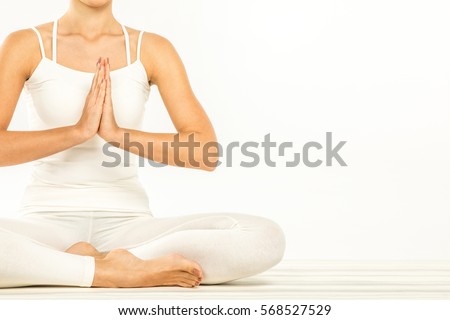 Woman sitting in lotus position with Namaste Mudra gesture isolated on white