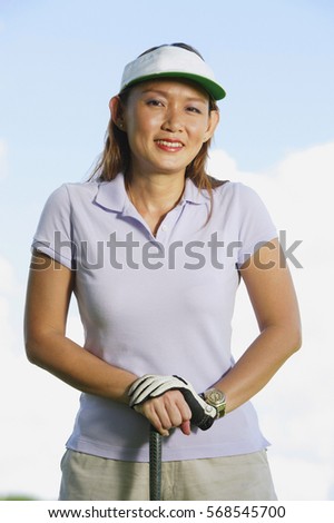 Woman wearing sun visor, leaning on golf club