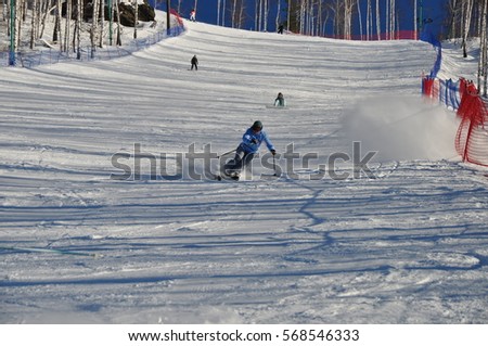 young woman goes skiing down the mountain slope in a cloud of snow powder