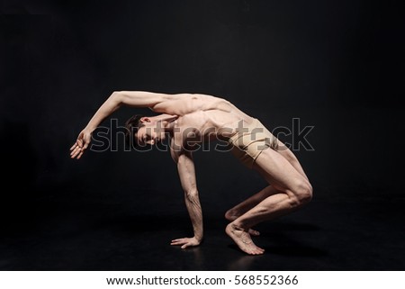Elastic young gymnast stretching in the dark lighted studio