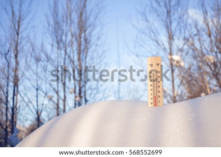 Thermometer in snow, the picture was taken from below on a blue sky background