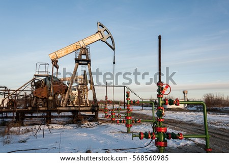 Oil pump jack and wellhead in the oilfield. Oil and gas concept.