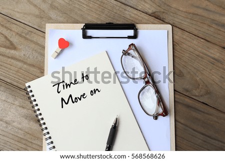 Time to move on - simple concept of text on notebook, clipboard, pen and glasses on wooden table. top view