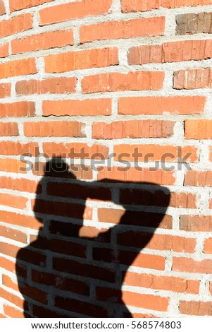 Shadow of man photographer taking picture showing in brick wall
