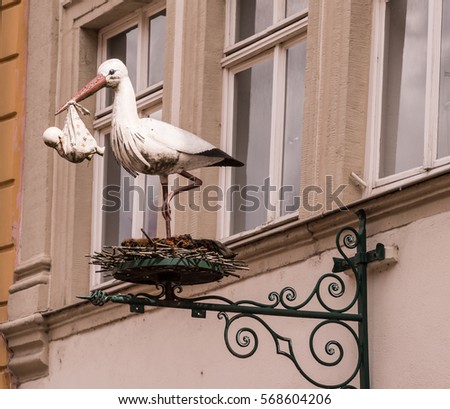 Old European Store sign of a Stork carrying a Baby Royalty-Free Stock Photo #568604206