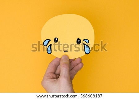 Sad emoji. Male hand holding a yellow emotion face with a hand drawn expression
