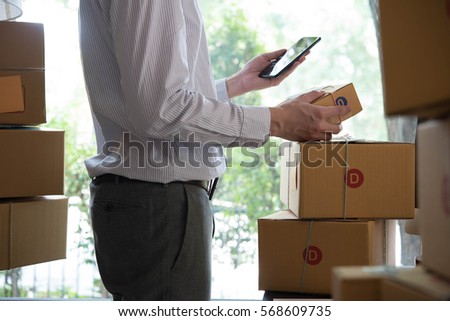 Businessman use smartphone thinking with pile of parcel on work desk