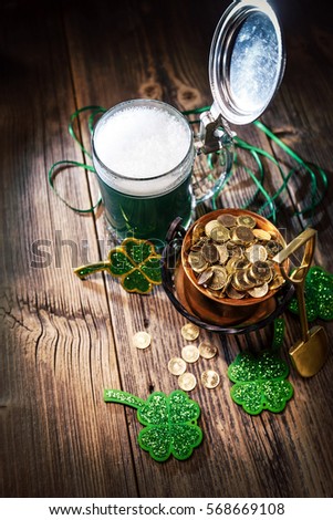 Glass of green beer and cauldron with coins