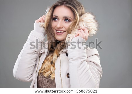 Nice Shy Hipster Girl in Winter Clothes,cream jacket with fur, beautiful blonde girl  - Stock image.