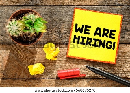 We are hiring / Paper sticker with inscription we are hiring and plant in pot, pen on wooden planks background