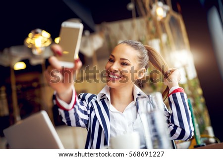 Young beautiful woman taking selfie at cafe bar.