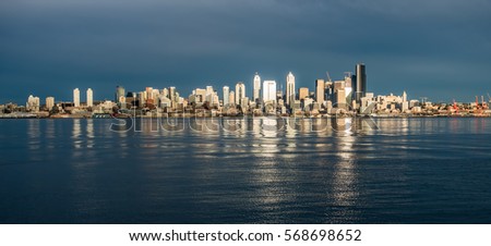 As the sun sets the buildings of the Seattle skyline are reflected in Elliott Bay.