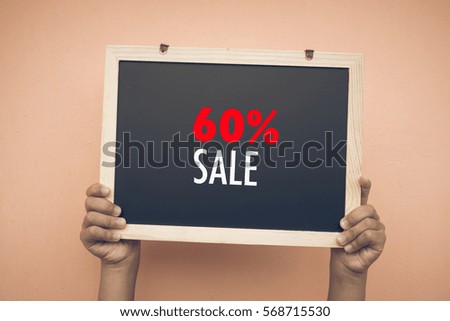 Hand holding chalk board with 60% SALE wording at wooden background. Motivation, positive wishes, business, finance, education concept

