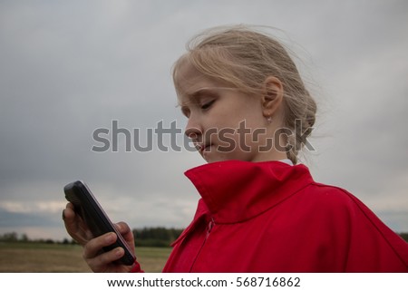 Girl with cell phone and cloudy sky background