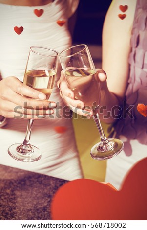 Cropped image of women toasting champagne flute against love heart pattern