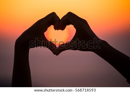Silhouette hand in the heart shape at the sky sunset background. concept love valentine day 