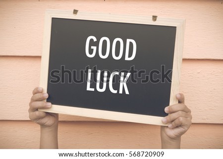 Hand holding chalk board with GOOD LUCK word at wooden background. Motivation, positive wishes, business, finance, education concept