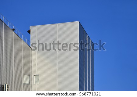 Photo of industrial high-rise building with perfect quality siding in sunlight. The huge building is completely covered with a striped metallic embossed sheets