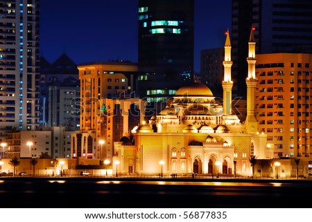 A view of a beautiful modern mosque along the lagoon at night