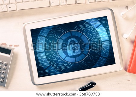 Business workplace with office stuff and tablet with padlock icon on screen