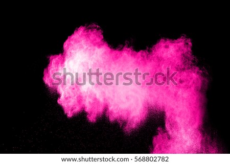 Freeze motion explosion of pink dust on a black background. By throwing talcum powder out of hand. Stopping the movement of pink holi powder on dark background.