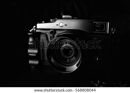 Moody stylish rangefinder style digital camera shot in low-key against black background.