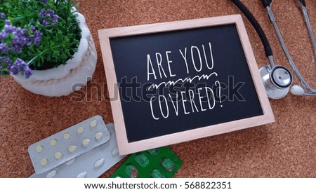 Stethoscope, Medicine, Chalk board and flower with inscription are you covered? on a wooden table. Medical and health care concept.

