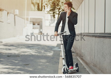 young man on the scooter walks through the city on Sunny day