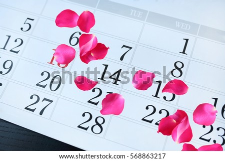 Calendar page with pink petals rose on February 14 of Saint Valentines day.
