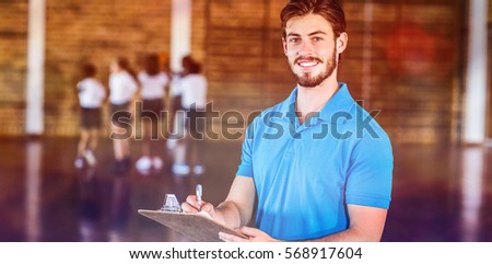 Portrait of sports teacher writing on clipboard in basketball court at school gym