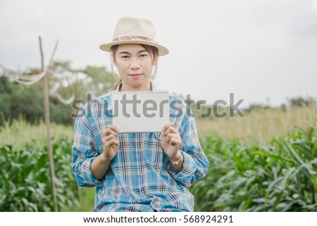 farmer woman holding blank white notebook in corn field