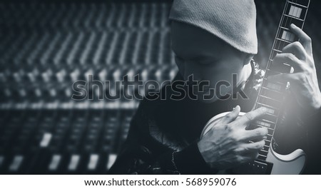 asian handsome male musician posing on electric guitar, studio mixer background. black and white
