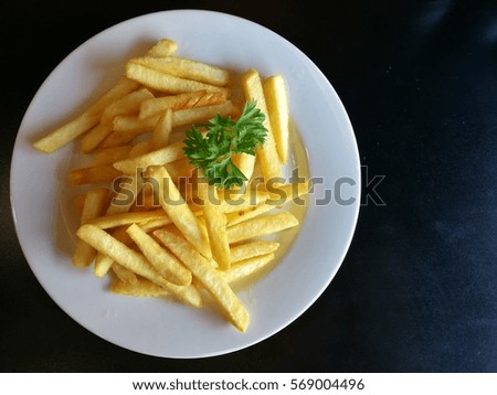 french fries in white dish on black table , low key tone picture