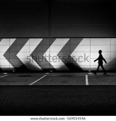 Lonely person walking in front of a arrow wall