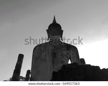 View of behind sculpture of the sitting Buddha at temple Wat Mahathat. Historical park of the Sukhothai city, Thailand. Picture in black and white.