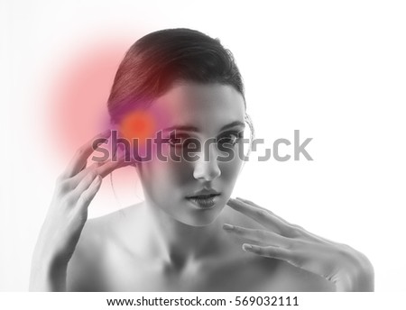 Black and white image of beautiful woman touching her hand to her temple where a red radiating spot is indicating tension or pain
