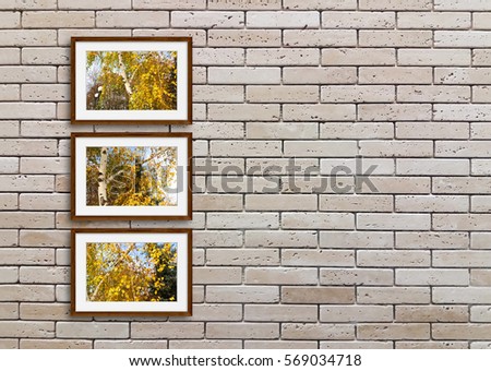 Three wooden frames with colorful autumn motif pictures on decorative bricks wall. Interiors decor idea mock up