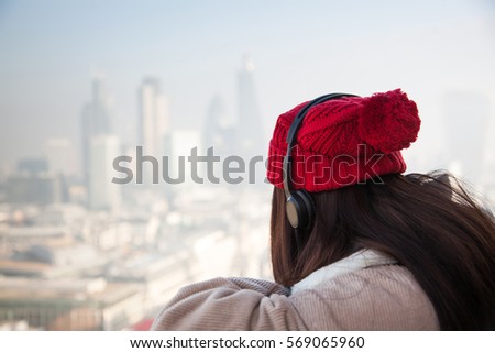 young woman with red hat looking at London skyline from St Paul's cathedral - happy tourist
