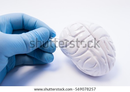 Concept of biopsy of brain tissue. Surgeon holding puncture needle and is preparing to puncture of the brain to capture nerve cells. Invasive diagnosis of brain diseases such as Parkinson's disease