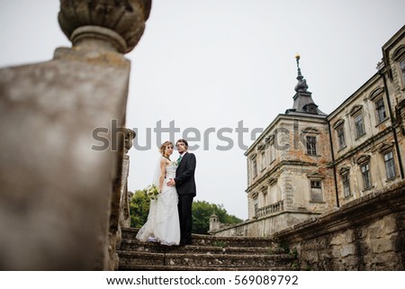Loving wedding couple at their happy wedding day background old vintage castle on cloudy weather.